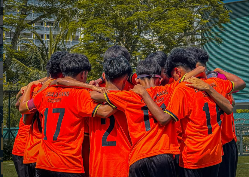 CCKSS football team in a pre-match huddle during a competitive school football match.